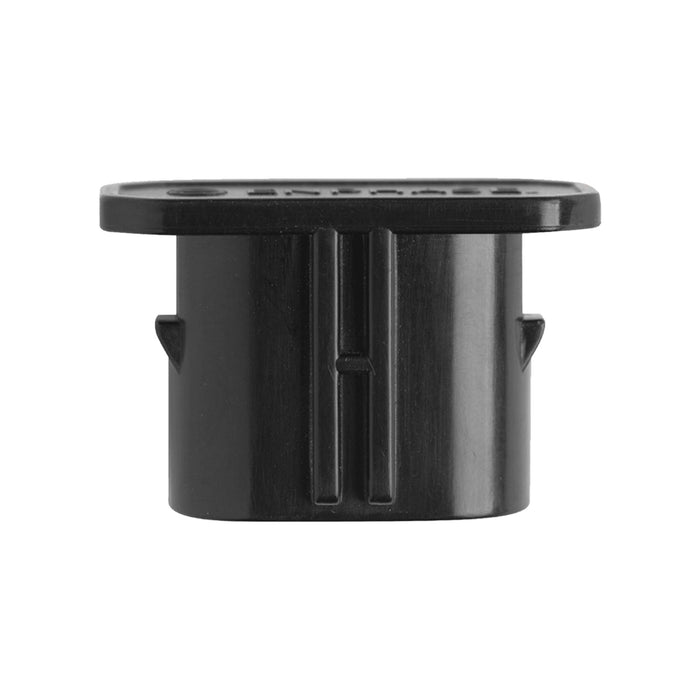 The black plastic cylindrical object with an oval flat top, featuring grooves and small protruding tabs on the sides, suggests it could be the Enphase Q-Seal-10 Female Sealing Cap by Enphase Energy for Q Cable connectors in an electronic assembly.