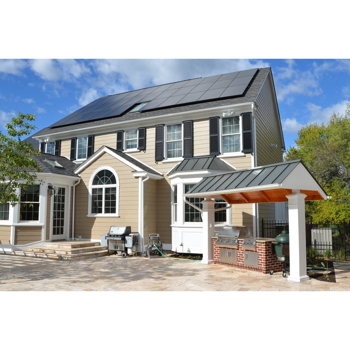 A two-story house with beige siding and black shutters features SunPower 405W solar panels on the roof. The yard includes a built-in outdoor grill and a patio with a stone surface, all set under a partly cloudy blue sky, emphasizing the efficiency of its sustainable energy solutions.