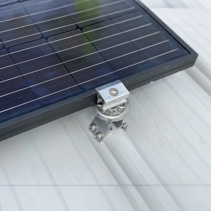 Close-up of a solar panel on a metal roof, featuring the S-5! PV Kit 2.0 EdgeGrab, which highlights its robust mounting solution with the metal bracket system. The S-5! attachment mechanism is clearly visible against the light-colored, ribbed surface, ensuring that solar panels are securely in place.