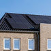 A brick house with SunPower 405W Solar Panels gleams under a clear blue sky. Four windows are visible on the second floor, nestled beneath the high-efficiency panels.